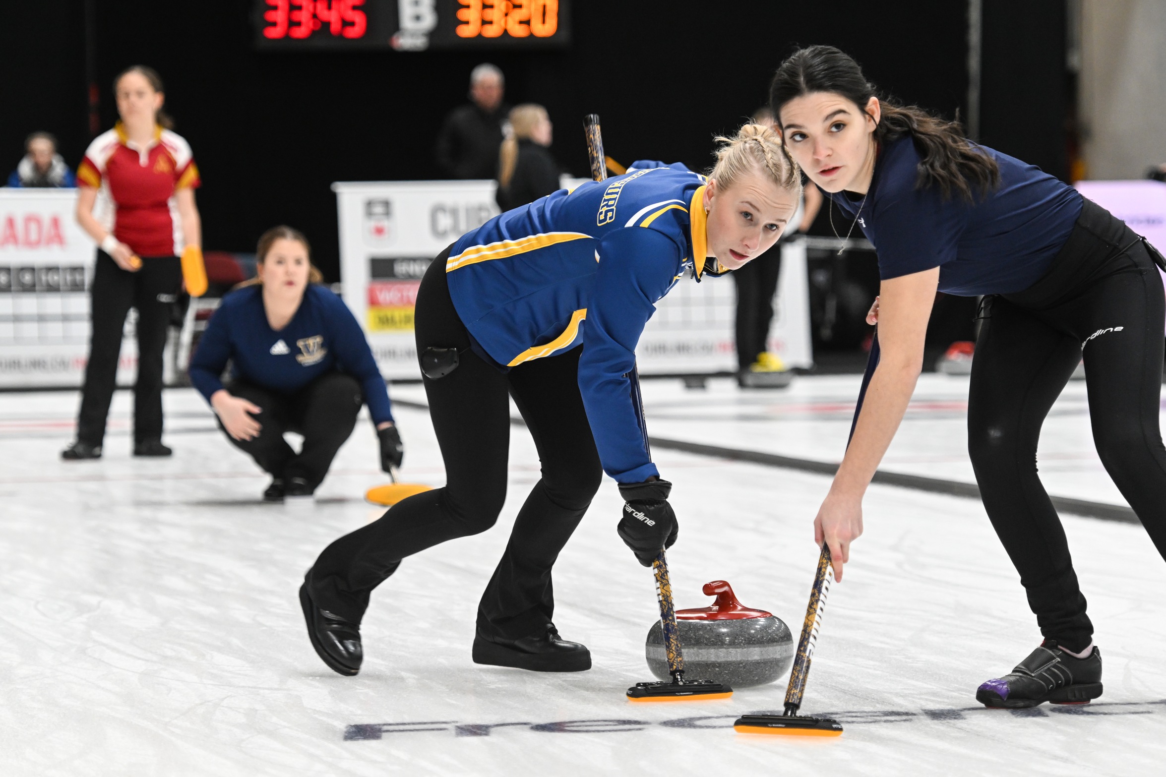 Mya Smith and Britney Malette sweeping a rock at the USPORTS Championships - Rob Blanchard (Curling Canada)